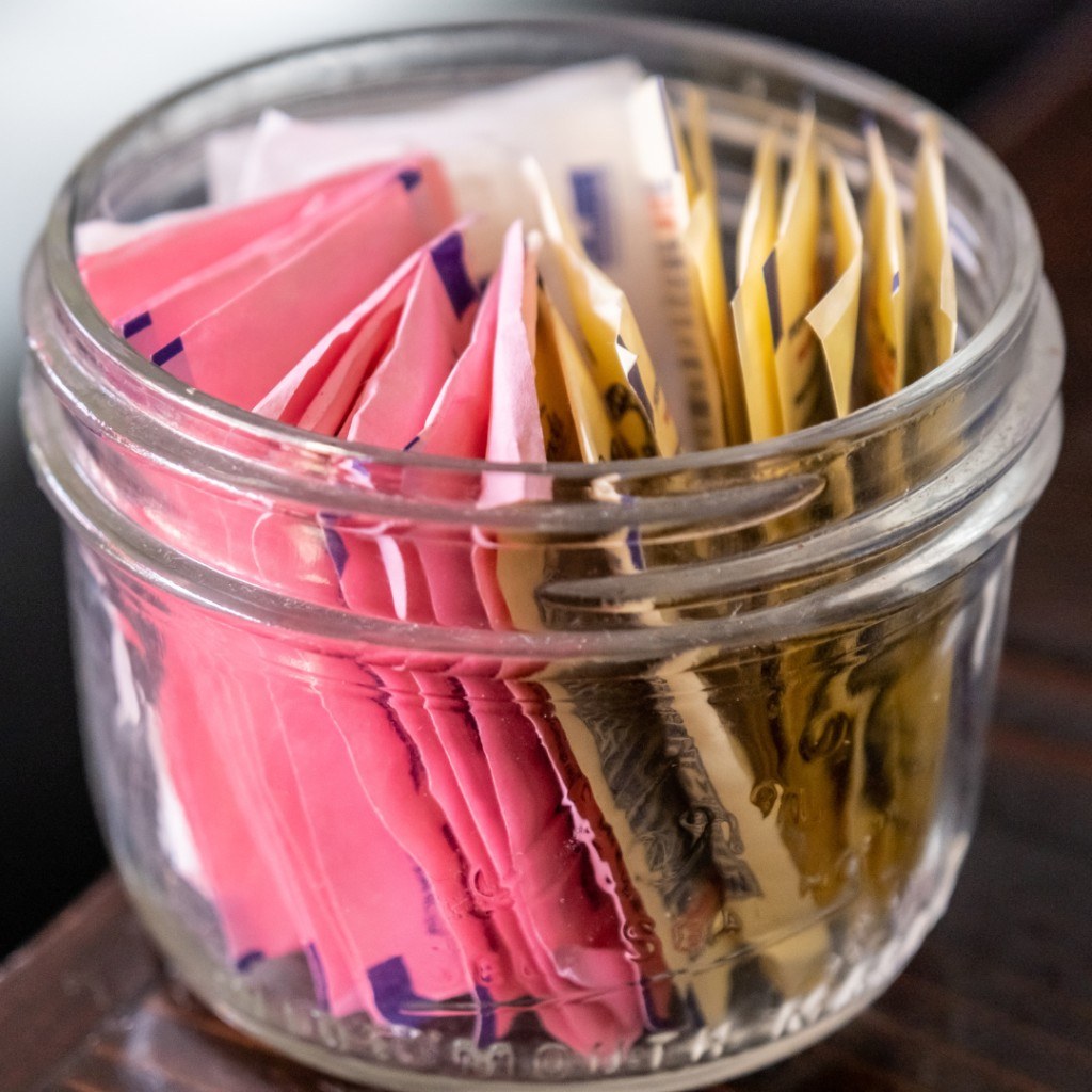 Jar of pink, yellow and blue sweetener packets